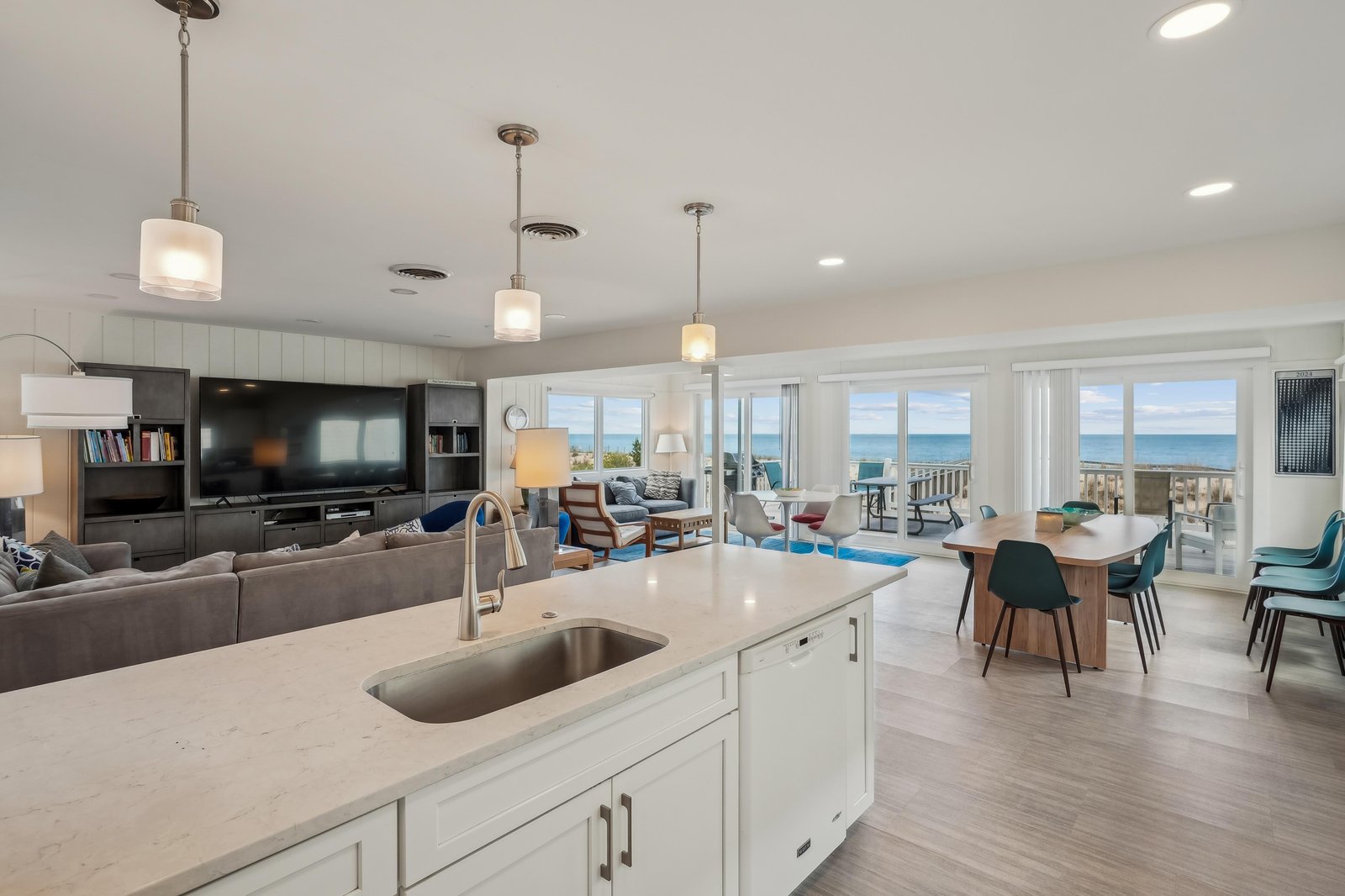 Step into your open-concept retreat where ocean breezes meet modern comfort. Your kitchen island invites meal prep with stunning sea views, while the living and dining areas flow seamlessly toward expansive windows framing the coastline beyond.