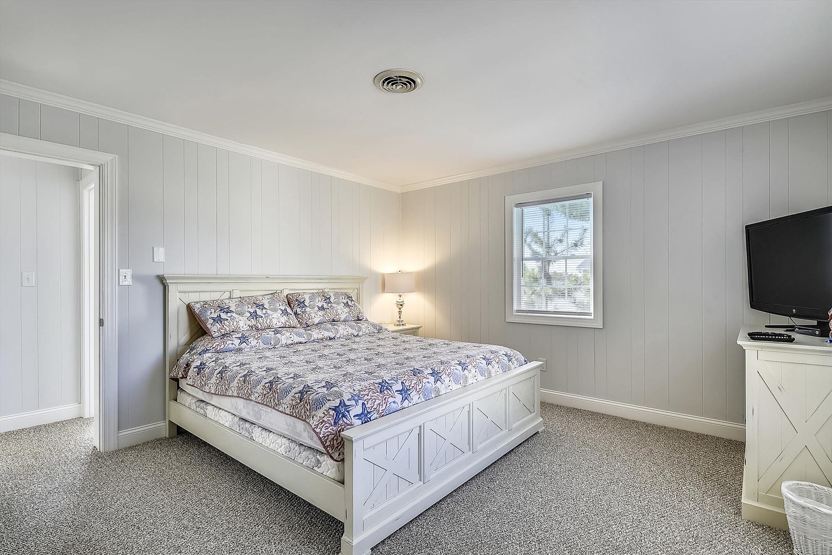 Sink into this inviting queen bed with coastal-inspired linens after a day exploring. Soft carpeting, calming gray tones, and ample natural light create your peaceful retreat.