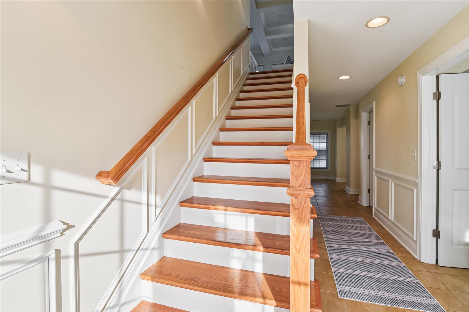 A welcoming entryway with gleaming hardwood stairs and warm natural light leading you to your upstairs retreat.