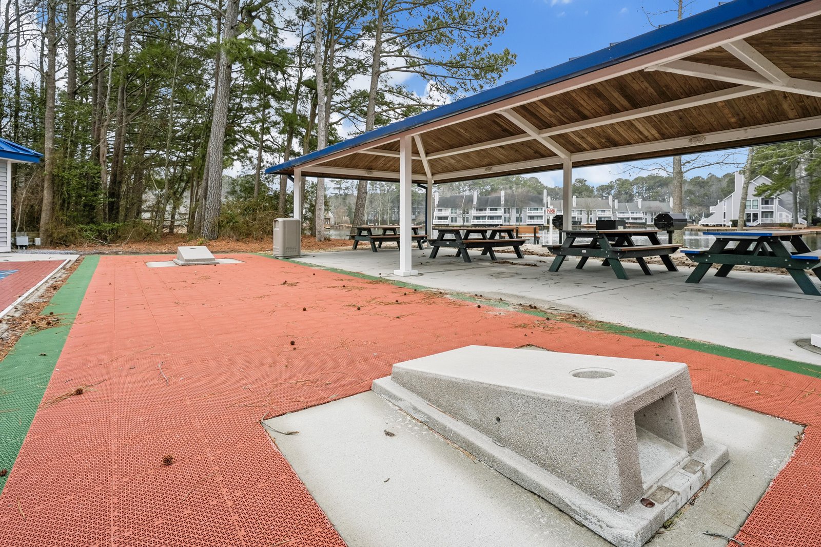 A covered pavilion with picnic tables sits among towering pines, offering a shaded spot for outdoor meals and gatherings during your stay.