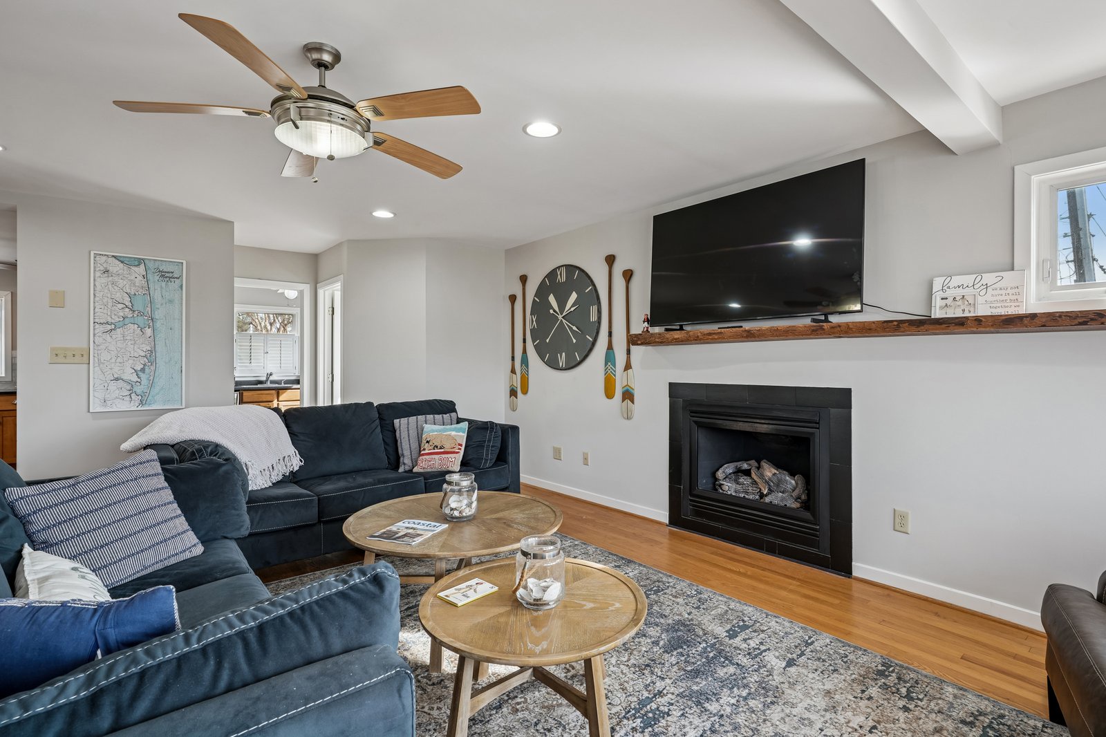 Relax on plush navy sofas by your cozy fireplace, where rustic paddle decor meets modern comfort in this inviting living space.