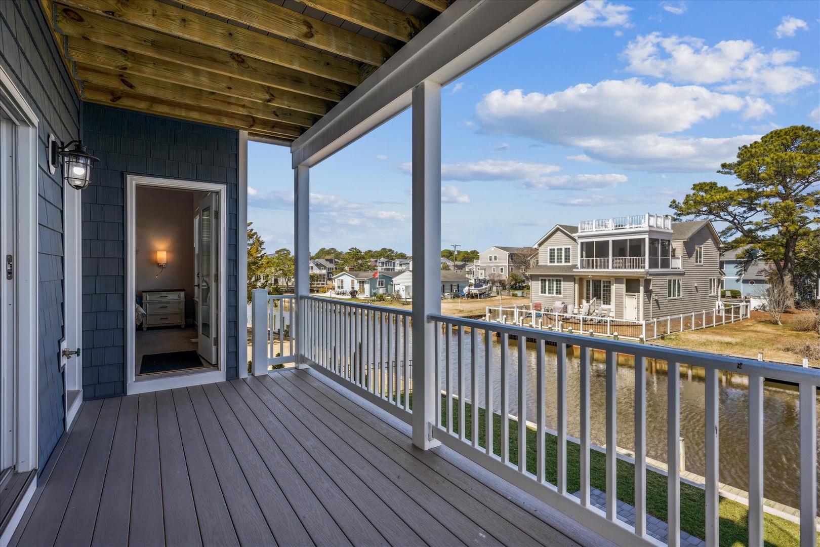 This covered balcony showcases serene waterfront views of the canal and neighboring coastal homes, a perfect spot to start your day with morning coffee or unwind as the sun sets.