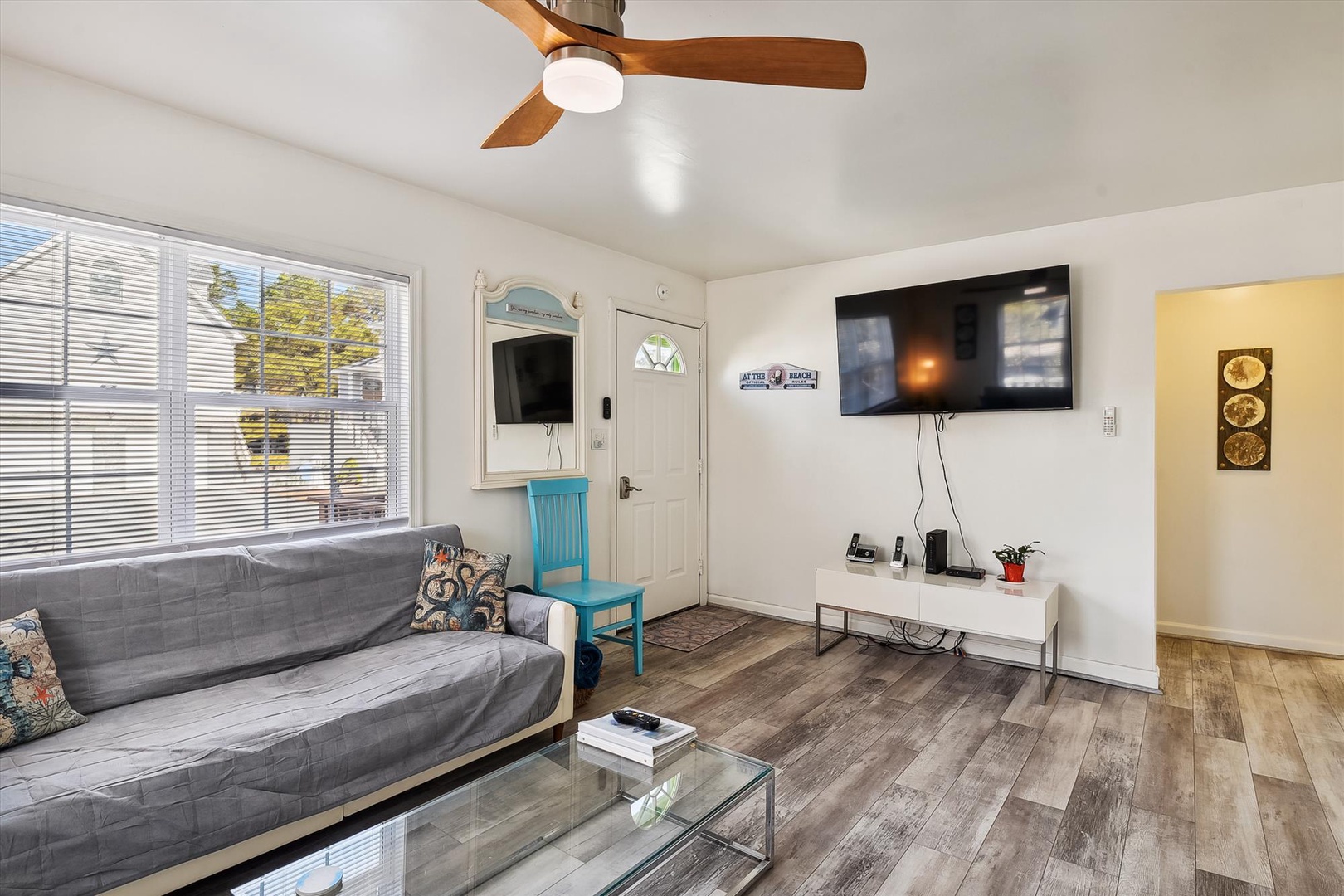 Unwind in your bright, open living space with a cozy sofa, ceiling fan, and flat-screen TV ready for your favorite shows. Natural light fills the room, inviting relaxation.