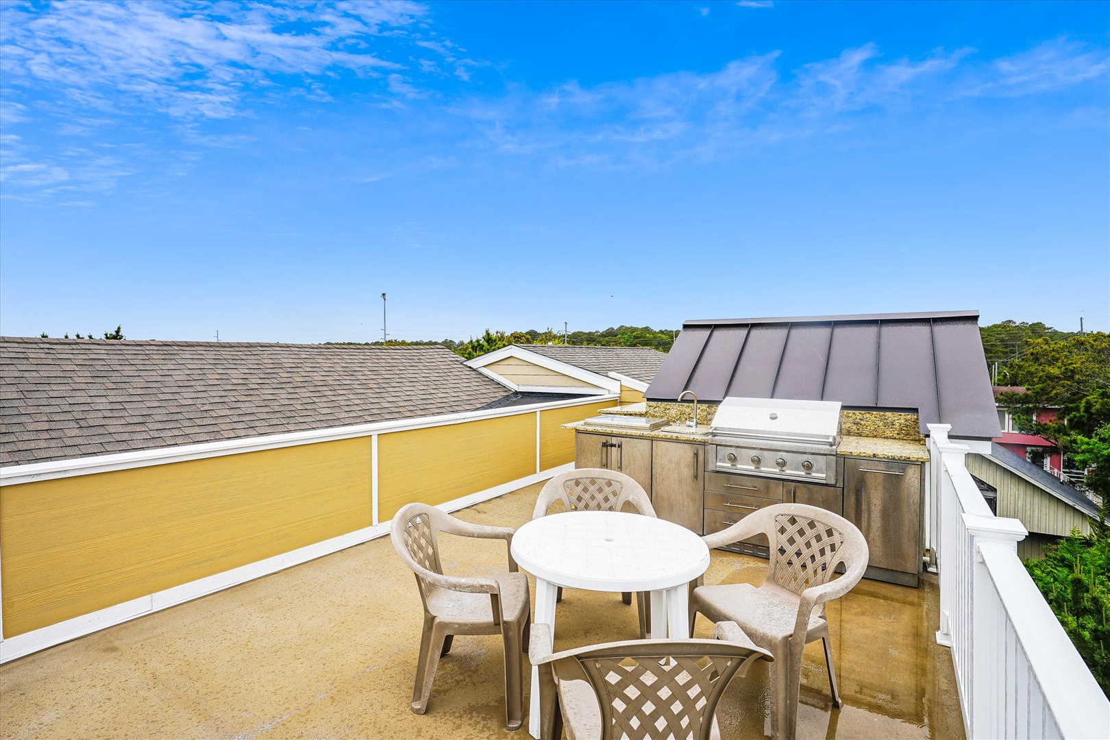 Rooftop terrace offers alfresco dining with a built-in grill and coastal views, perfect for outdoor entertaining under clear skies.