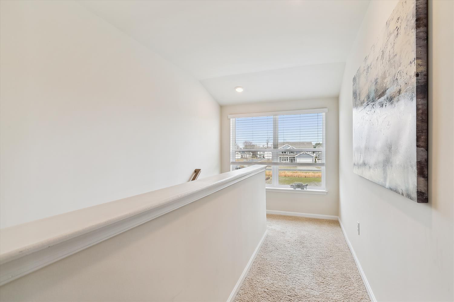 A bright upper-level hallway with a window overlooking the surrounding neighborhood, providing natural light and a sense of openness.