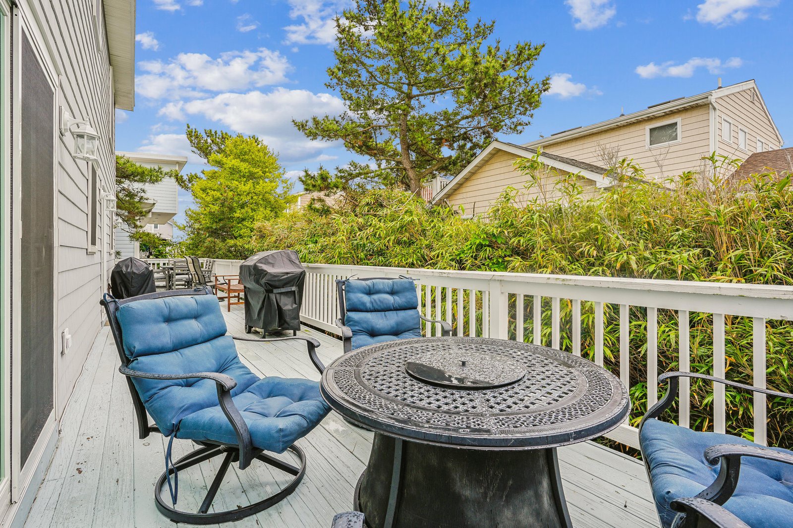Your private deck awaits with cozy cushioned seating and a spacious table—perfect for morning coffee or grilling evenings outdoors beneath clear skies and mature trees.