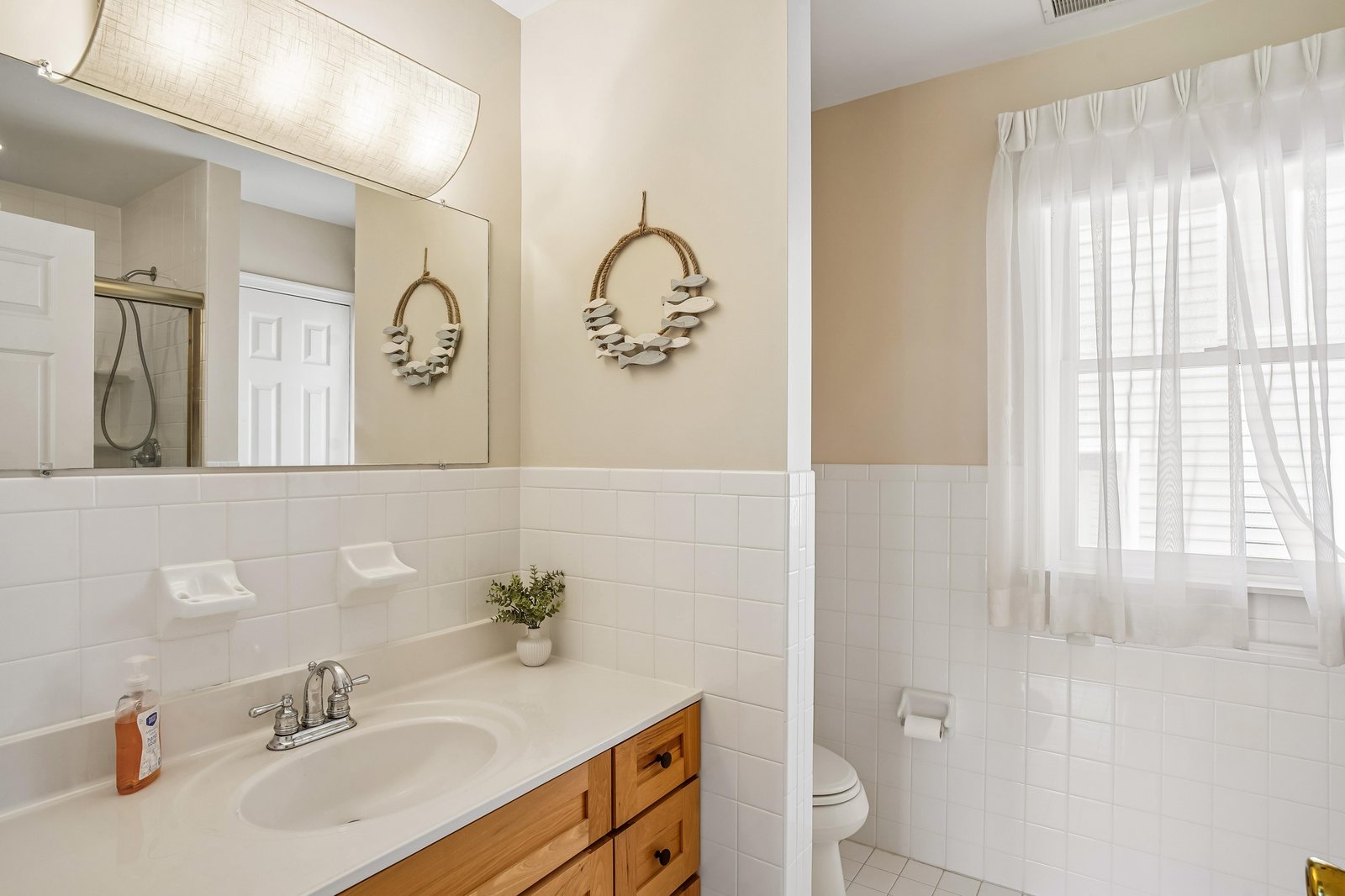 Step into your private bathroom featuring coastal-inspired decor, subway tile, natural wood vanity, and soft lighting that creates a peaceful retreat for your morning routine.