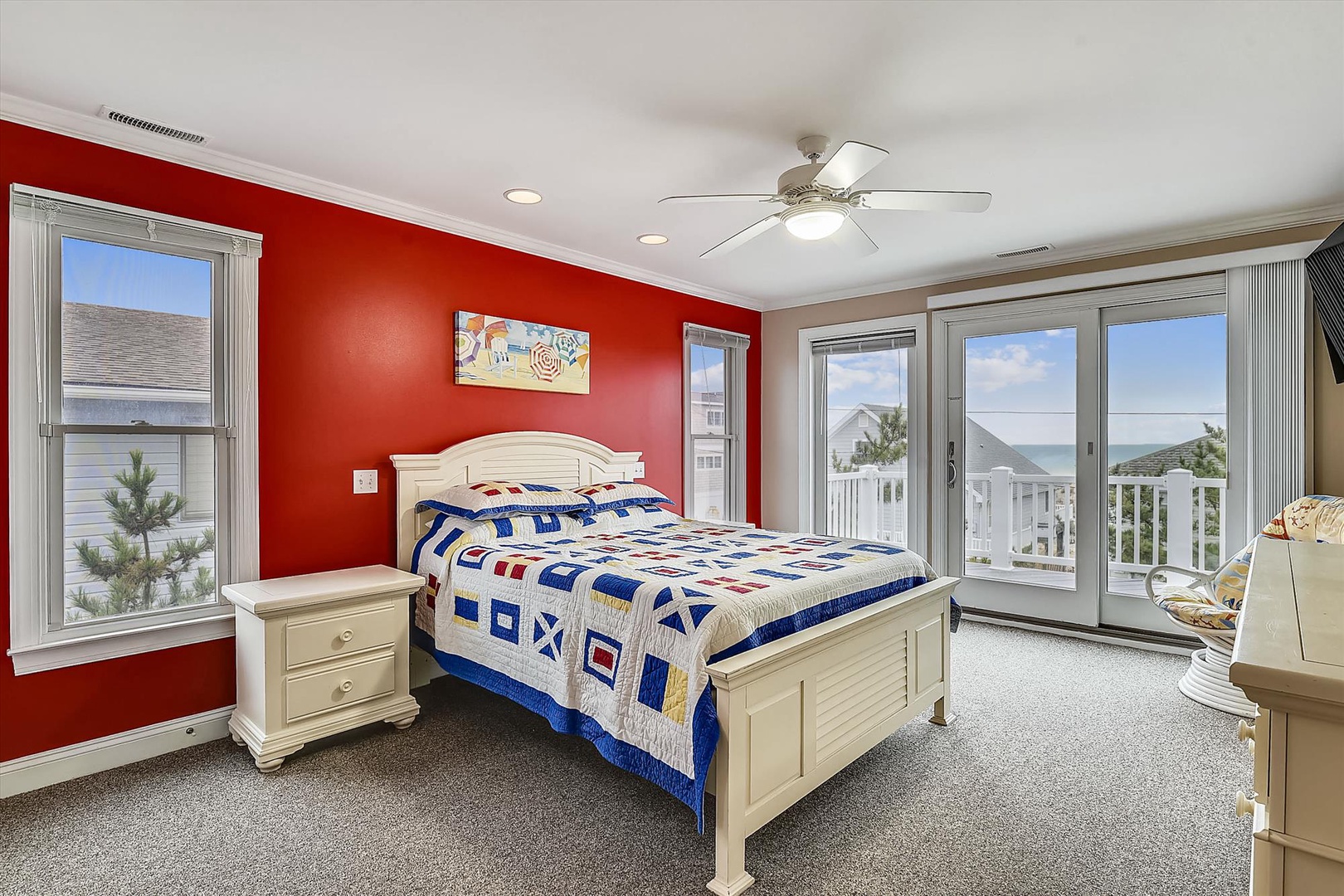 Step into your vibrant coastal bedroom where a nautical quilt invites peaceful sleep and glass doors open to ocean views that greet you each morning.