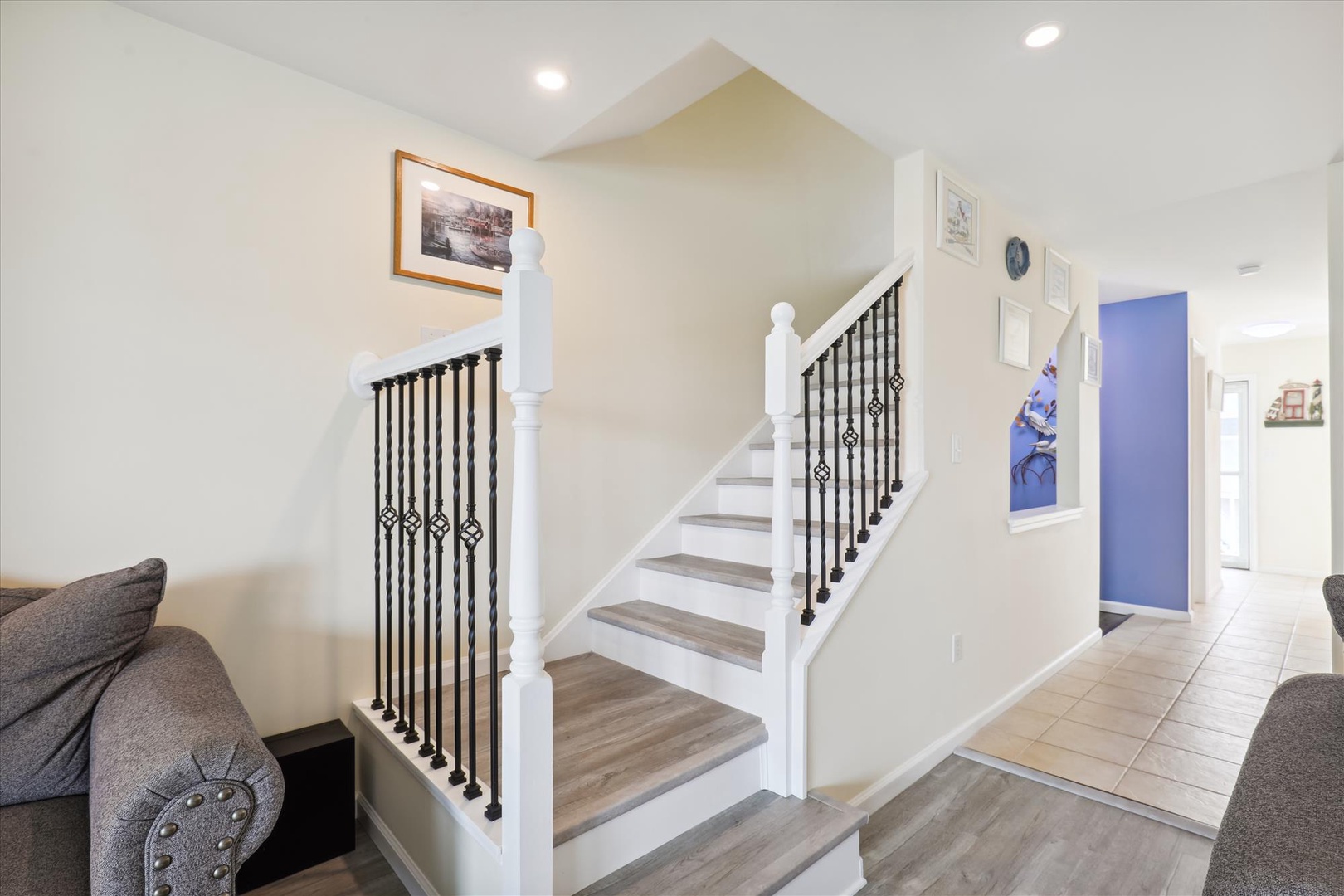 Step into your bright, modern entry with stylish stairway and comfortable seating. You'll love the blend of elegant railings and welcoming decor throughout this cozy space.