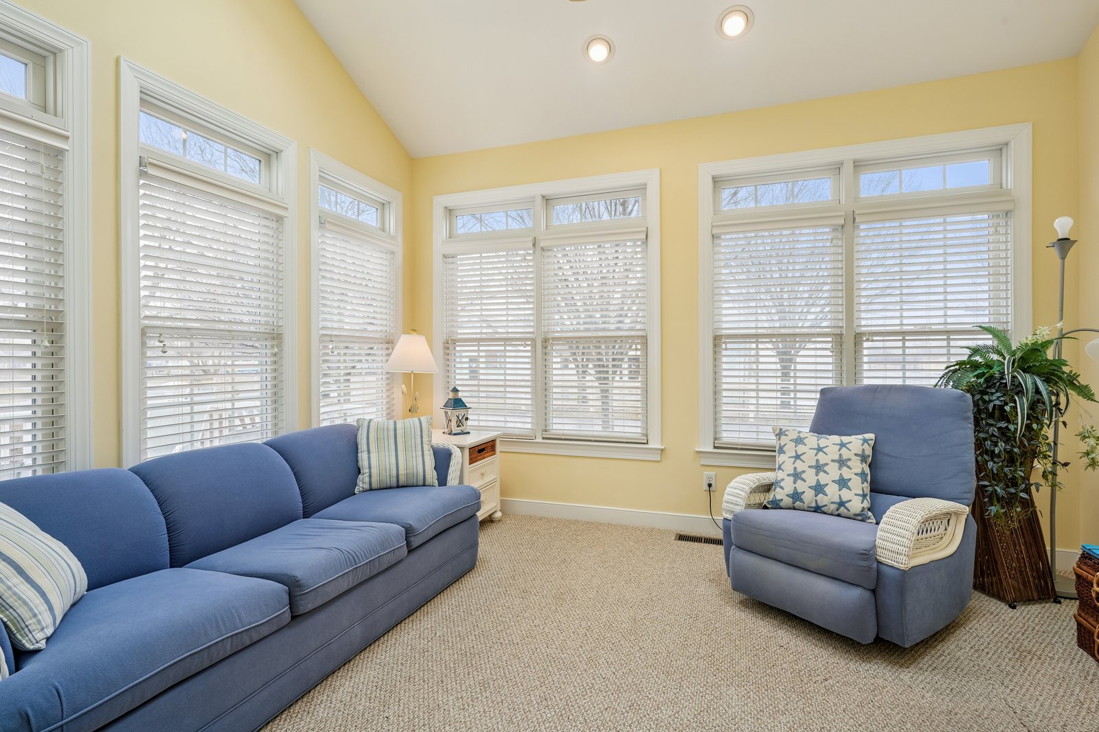 Sink into plush blue seating surrounded by warm yellow walls and natural light streaming through elegant windows.
