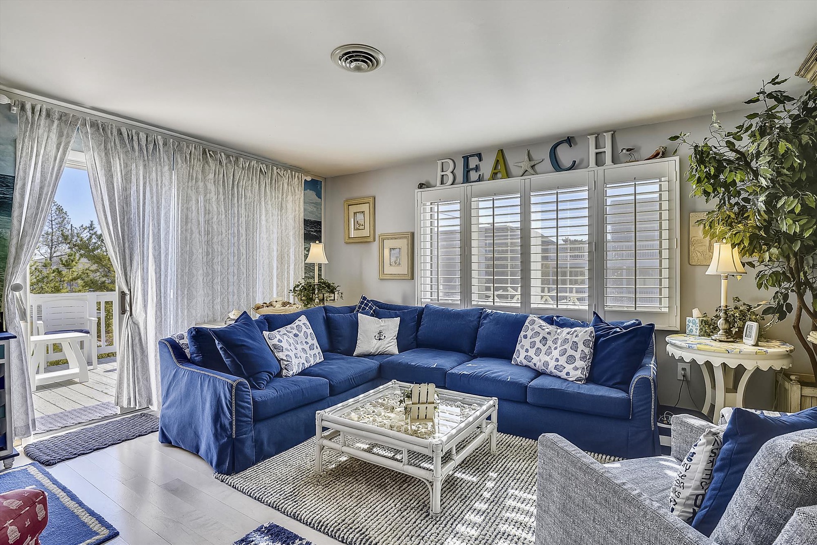 Sink into the plush coastal-blue sectional and let ocean breezes flow through open doors—your beachside escape awaits in this bright, inviting living space.