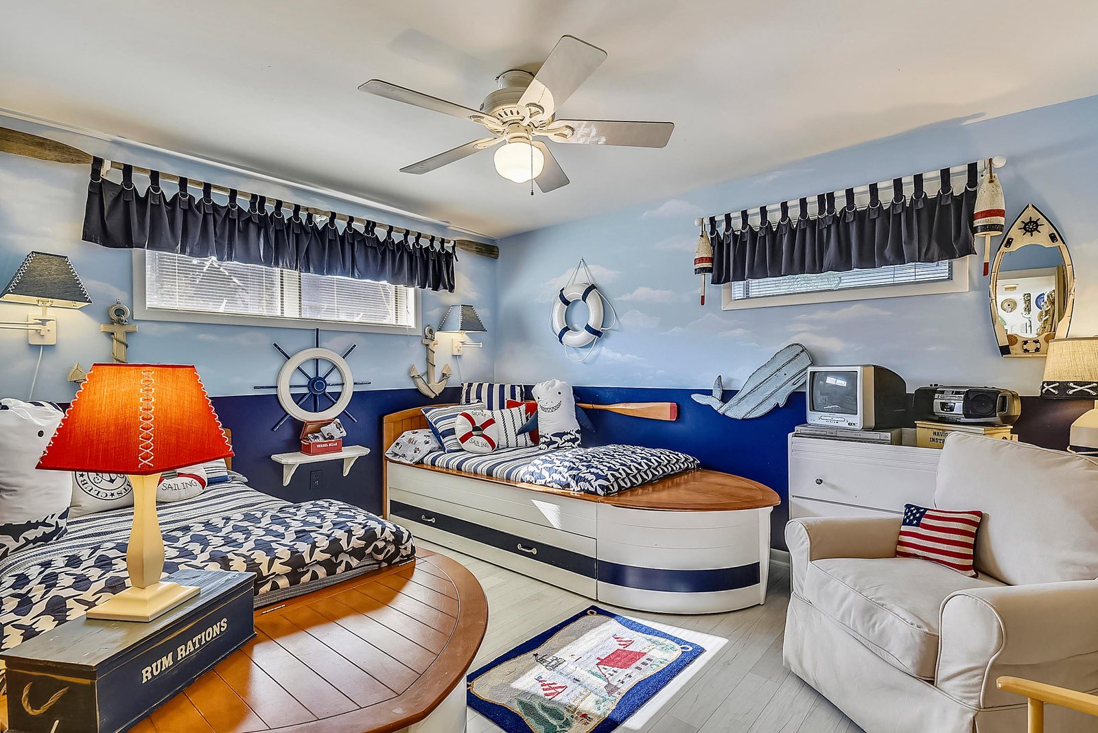 Step into this charming nautical-themed bedroom, where playful maritime details and cozy boat-shaped beds invite you to drift off to sleep surrounded by ocean-inspired décor.