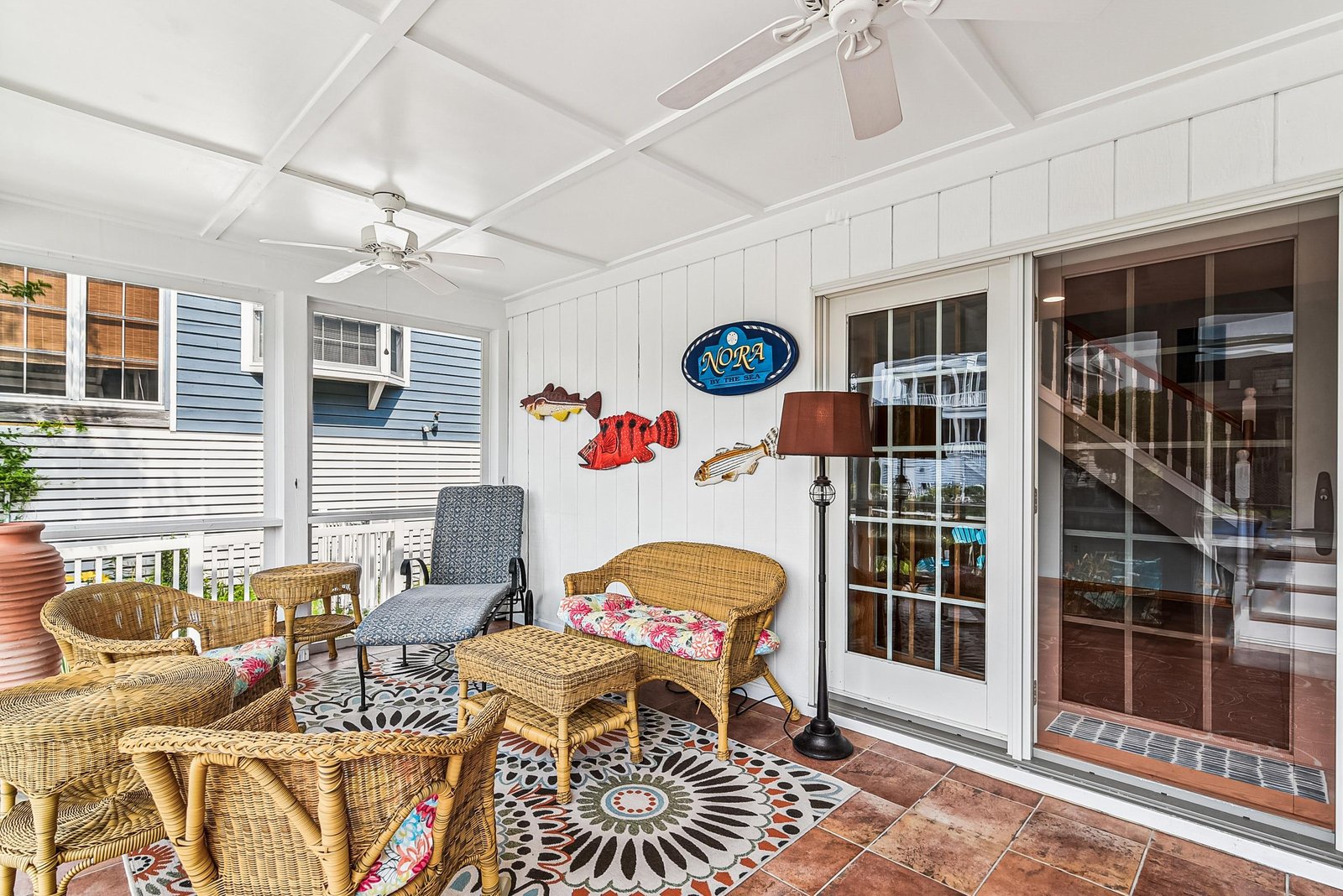 Step onto your covered patio where wicker seating and playful coastal decor create the perfect spot to unwind with morning coffee or an evening drink, all with a gentle breeze overhead.