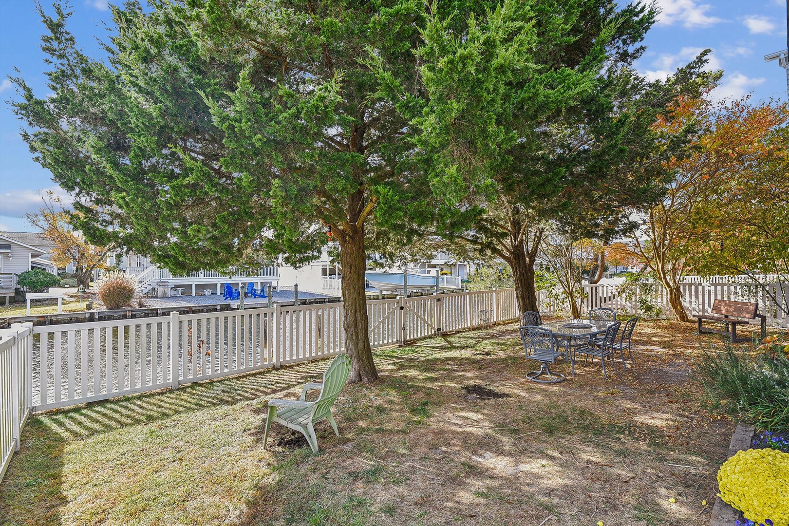 Private fenced backyard featuring mature shade trees, outdoor seating, and a peaceful setting perfect for morning coffee or evening relaxation near the waterfront.