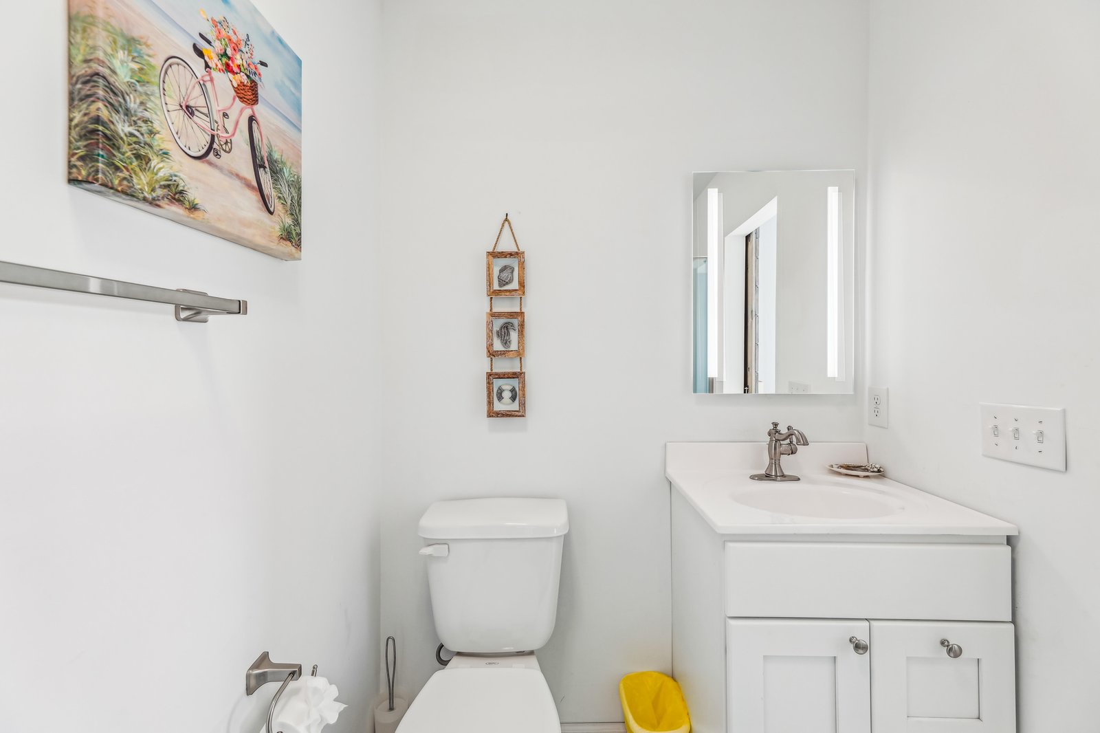 Bright, coastal-inspired bathroom with beach artwork, modern fixtures, and a cheerful pop of color to greet you each morning.