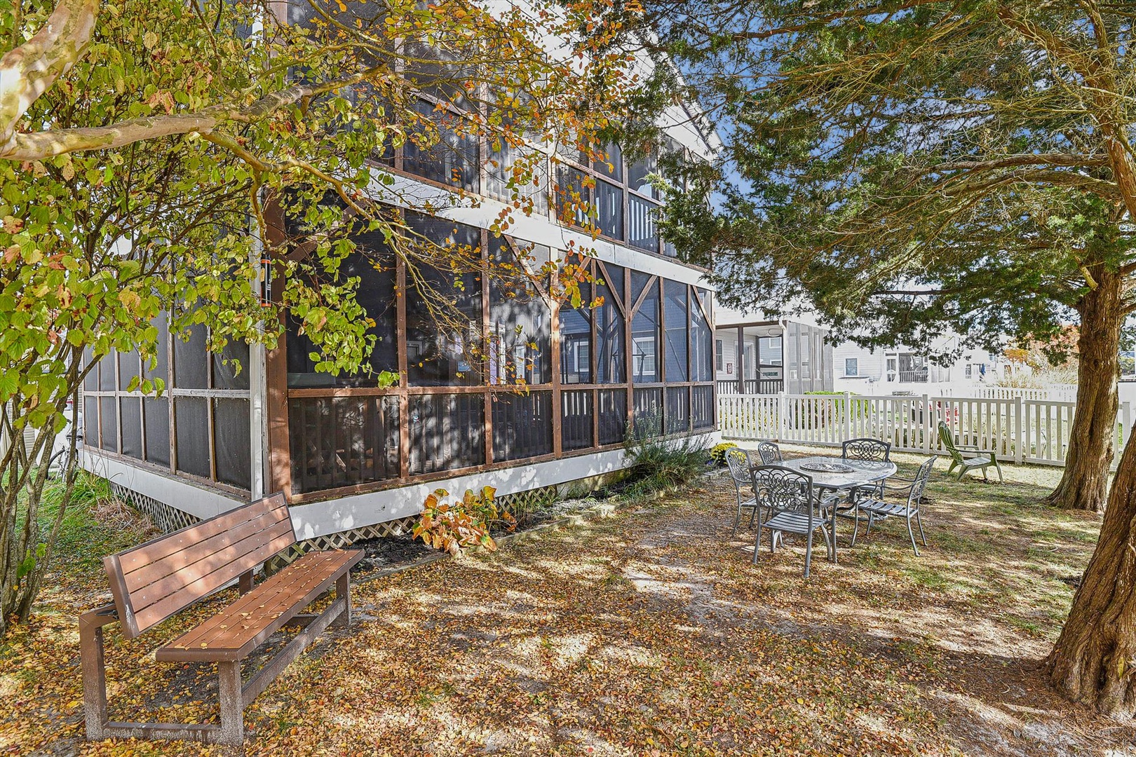 Private backyard retreat framed by mature trees and fall foliage, with a screened porch and outdoor dining space for your peaceful getaway.