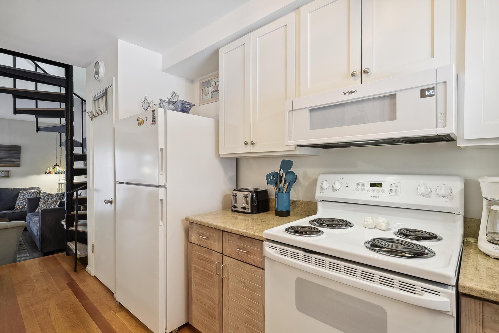 Your fully equipped kitchen features everything you need to prepare meals during your stay, with bright white cabinetry, modern appliances, and warm hardwood floors.