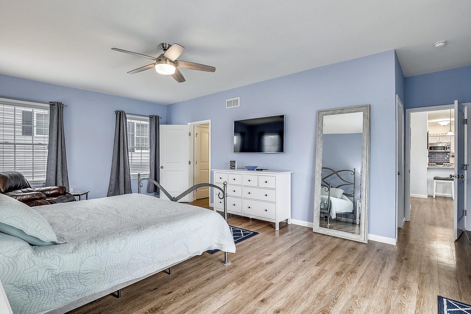 Relax in your spacious bedroom with soothing blue walls, a ceiling fan keeping you comfortable, and wood-style floors beneath your feet. Natural light streams through the windows, while your private ensuite awaits just steps away.