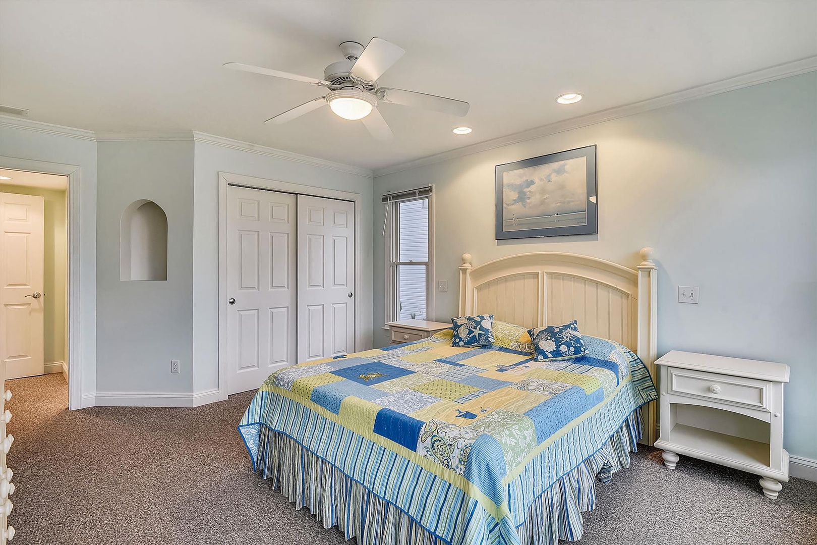 Unwind in your serene bedroom with soft coastal hues, a cozy ceiling fan, and charming décor—your peaceful retreat awaits after sun-soaked days.