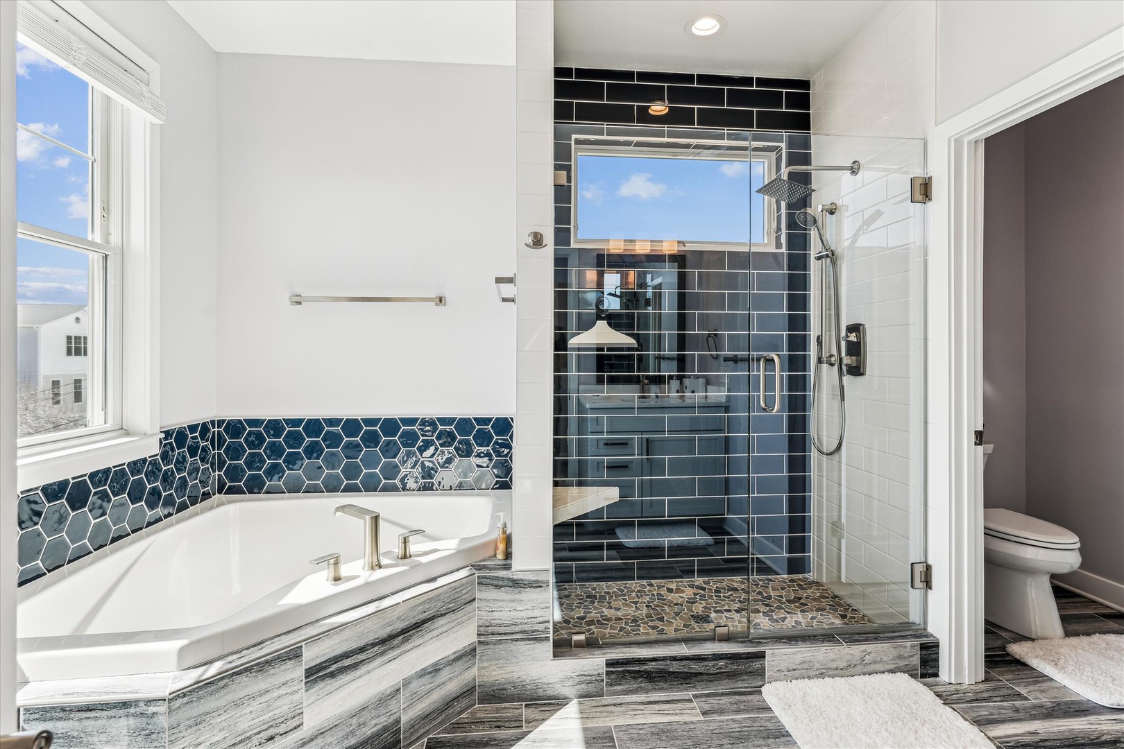 Unwind in your luxurious master bathroom with a soaking tub and stunning glass-enclosed shower featuring beautiful blue tilework.