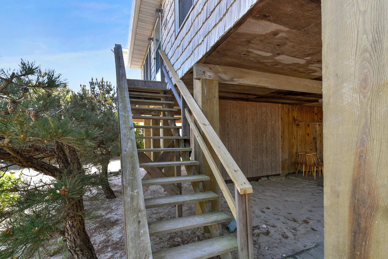 The wooden stairs lead up to the deck, with convenient storage space tucked underneath—perfect for keeping beach gear close at hand.