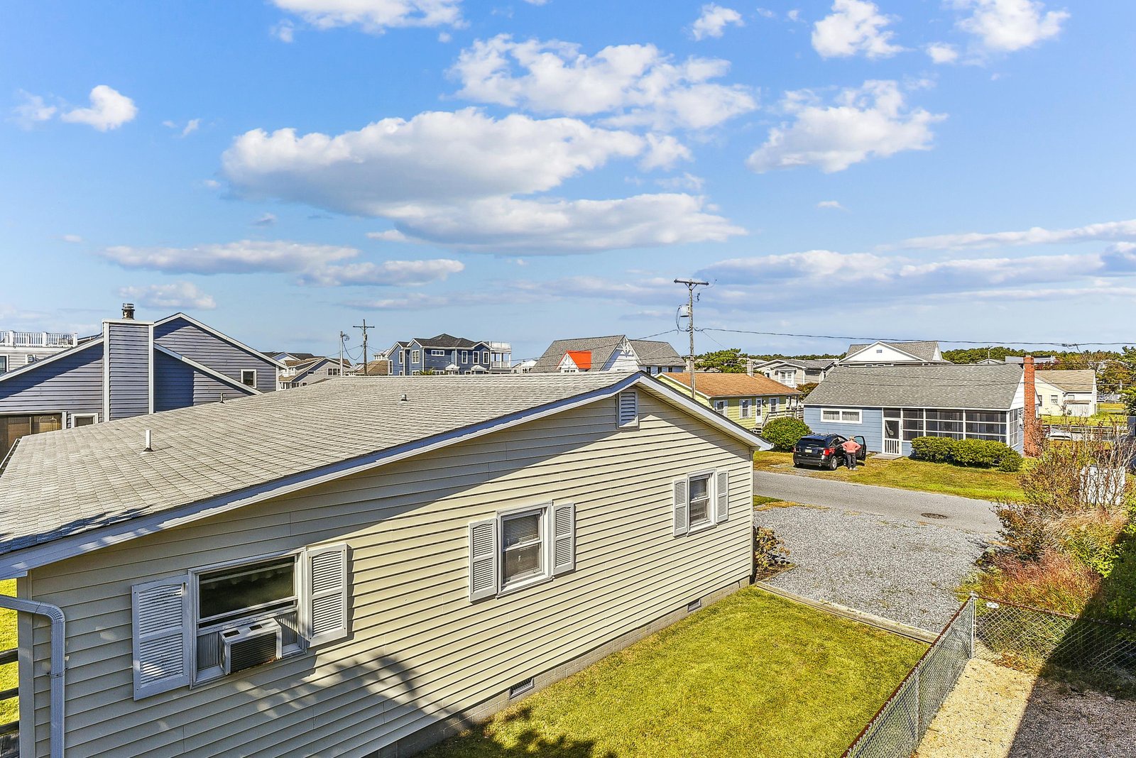 Charming coastal neighborhood exterior with nearby residential homes, parking, and open skies, perfectly situated for your beach getaway.