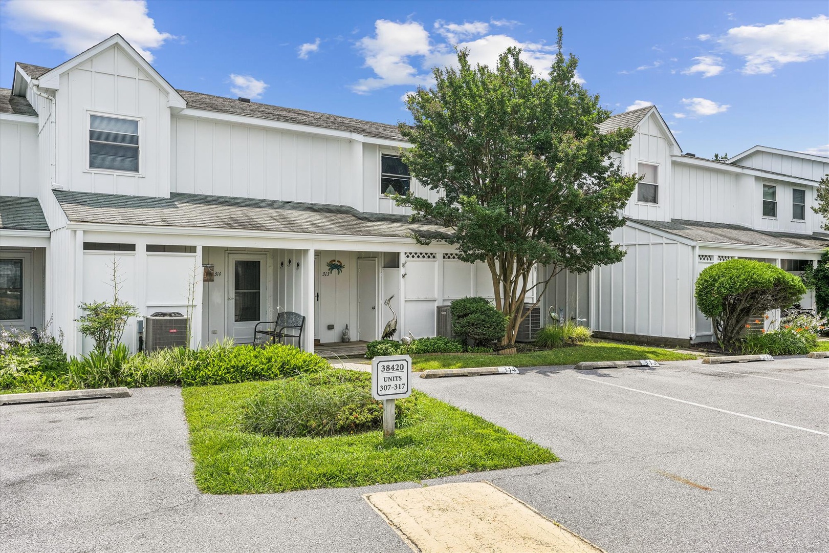 Freshly painted white townhomes with lush landscaping and mature shade trees in a peaceful residential community.