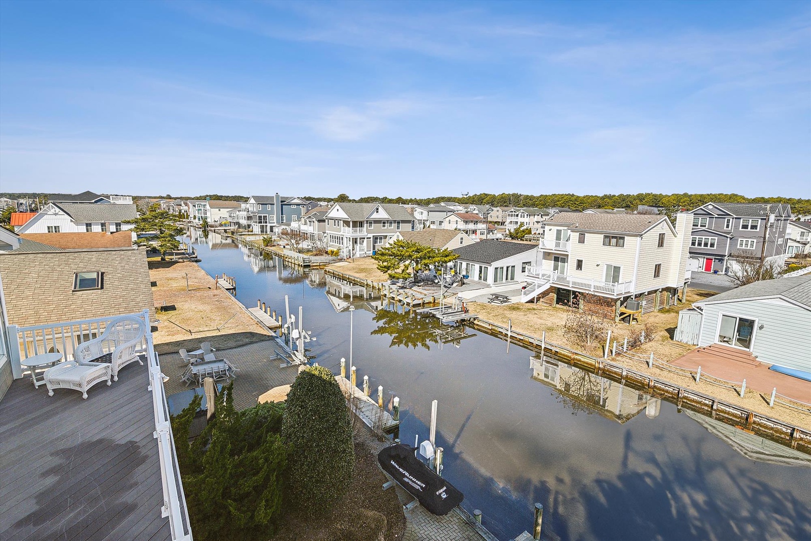 Waterfront residential community with private docks, canal access, and coastal homes nestled among mature trees beneath expansive blue skies.