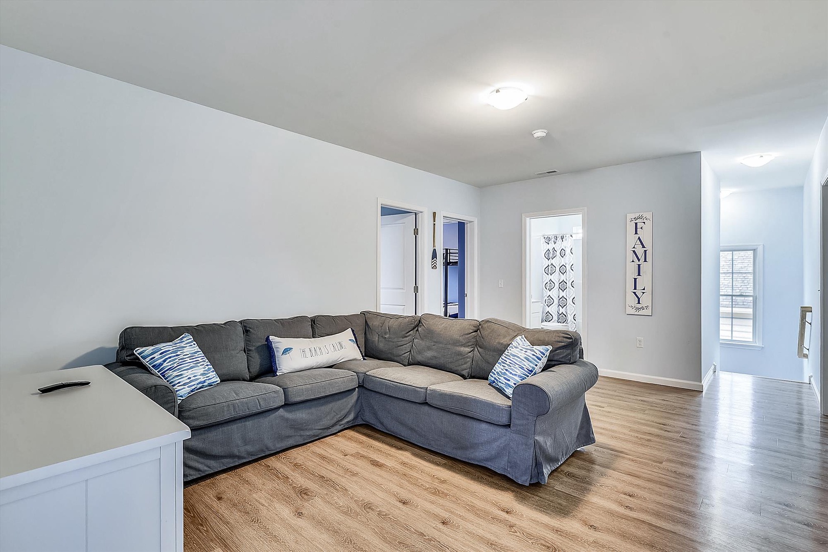 Sink into the plush sectional and feel instantly at home in your bright, open living space with warm wood floors and coastal-inspired touches.