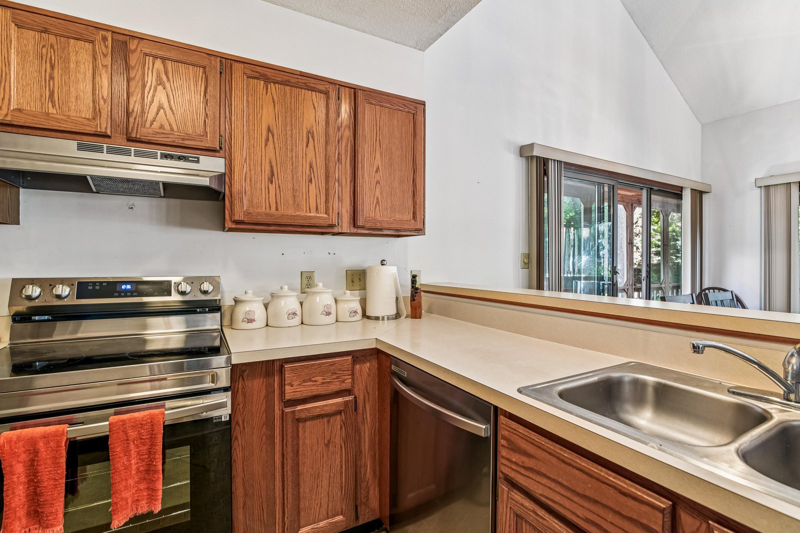 Your fully-equipped kitchen invites you to prepare meals with ease, featuring a modern stove, dishwasher, and plenty of counter space—all bathed in natural light from the adjacent dining area.