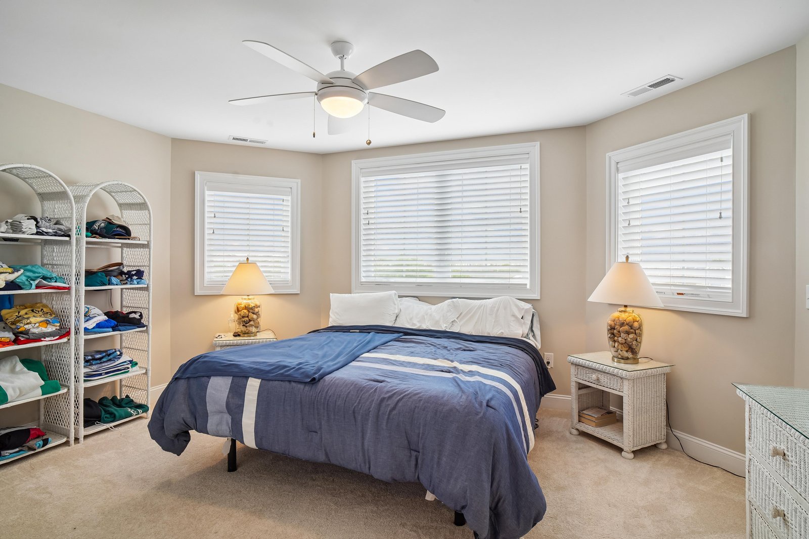 Your coastal-themed bedroom offers a restful retreat with soft natural light, ceiling fan, and nautical touches that evoke relaxed beachside living.