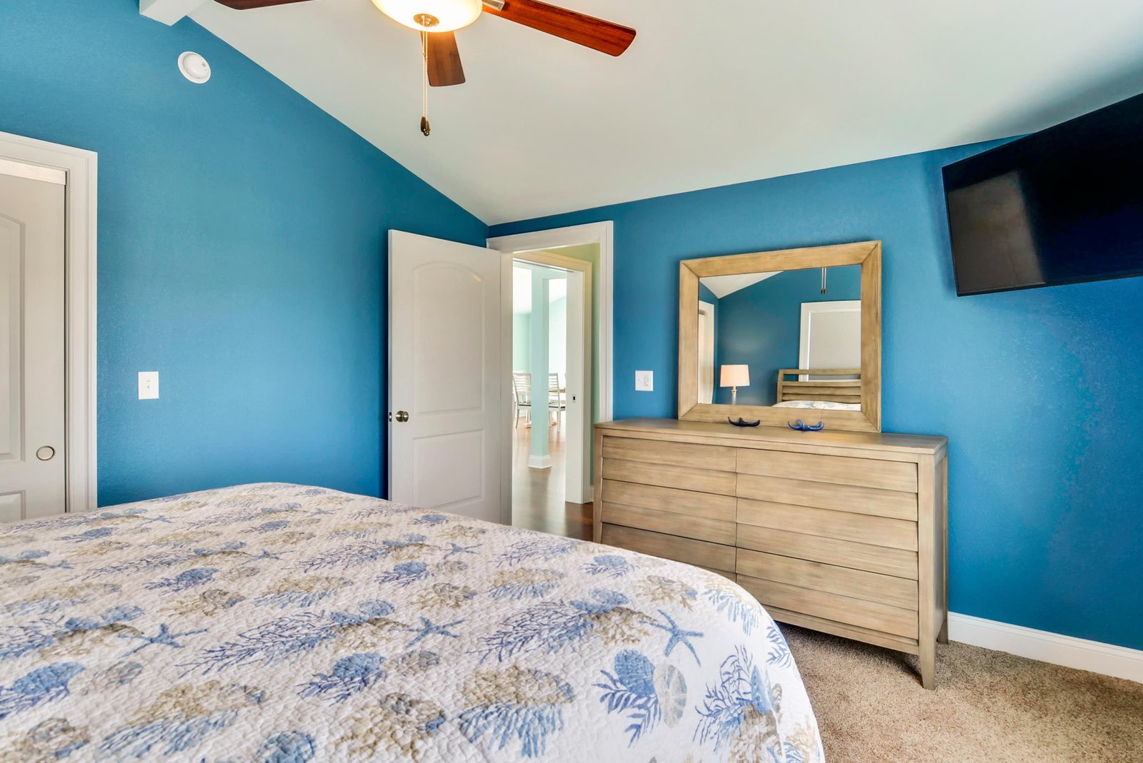 Relax in your calming coastal-blue bedroom, where crisp linens and a ceiling fan promise restful nights, and thoughtful touches like an ensuite bath and TV keep you comfortable.