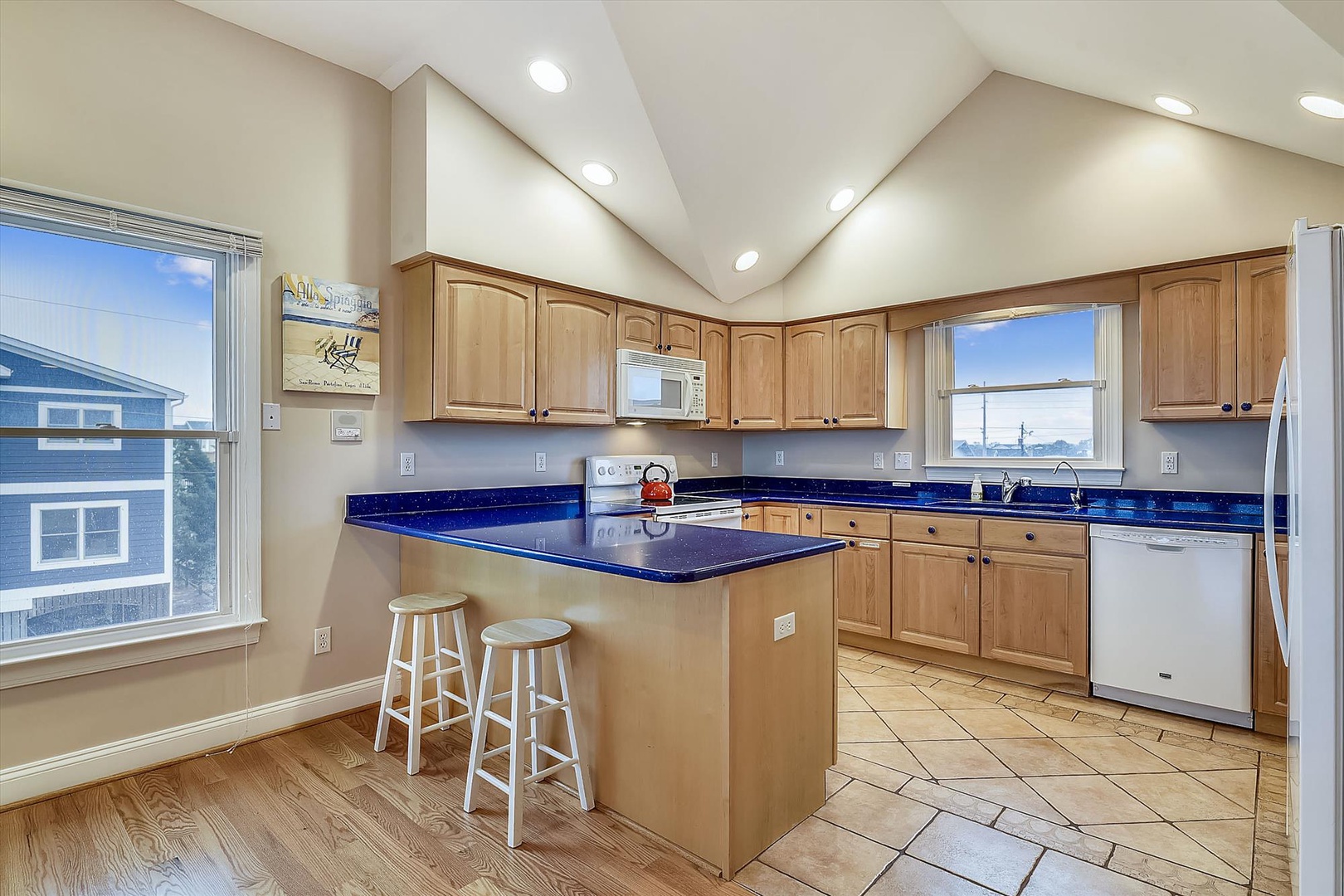 Your fully equipped kitchen with bold blue countertops, an island with bar seating, and abundant natural light makes meal prep easy and enjoyable.