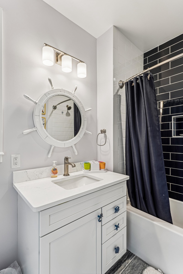 Step into your private oasis with a chic nautical twist—a ship's wheel mirror, sleek fixtures, and crisp subway tile invite you to unwind and refresh in style.