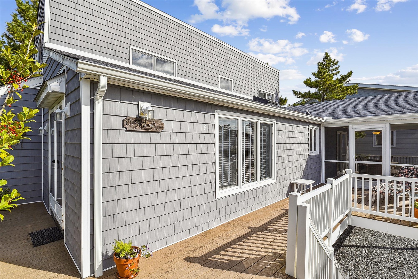 This bright, modern property features a welcoming deck and comfortable outdoor living space, perfect for enjoying sunny afternoons and scenic blue skies.