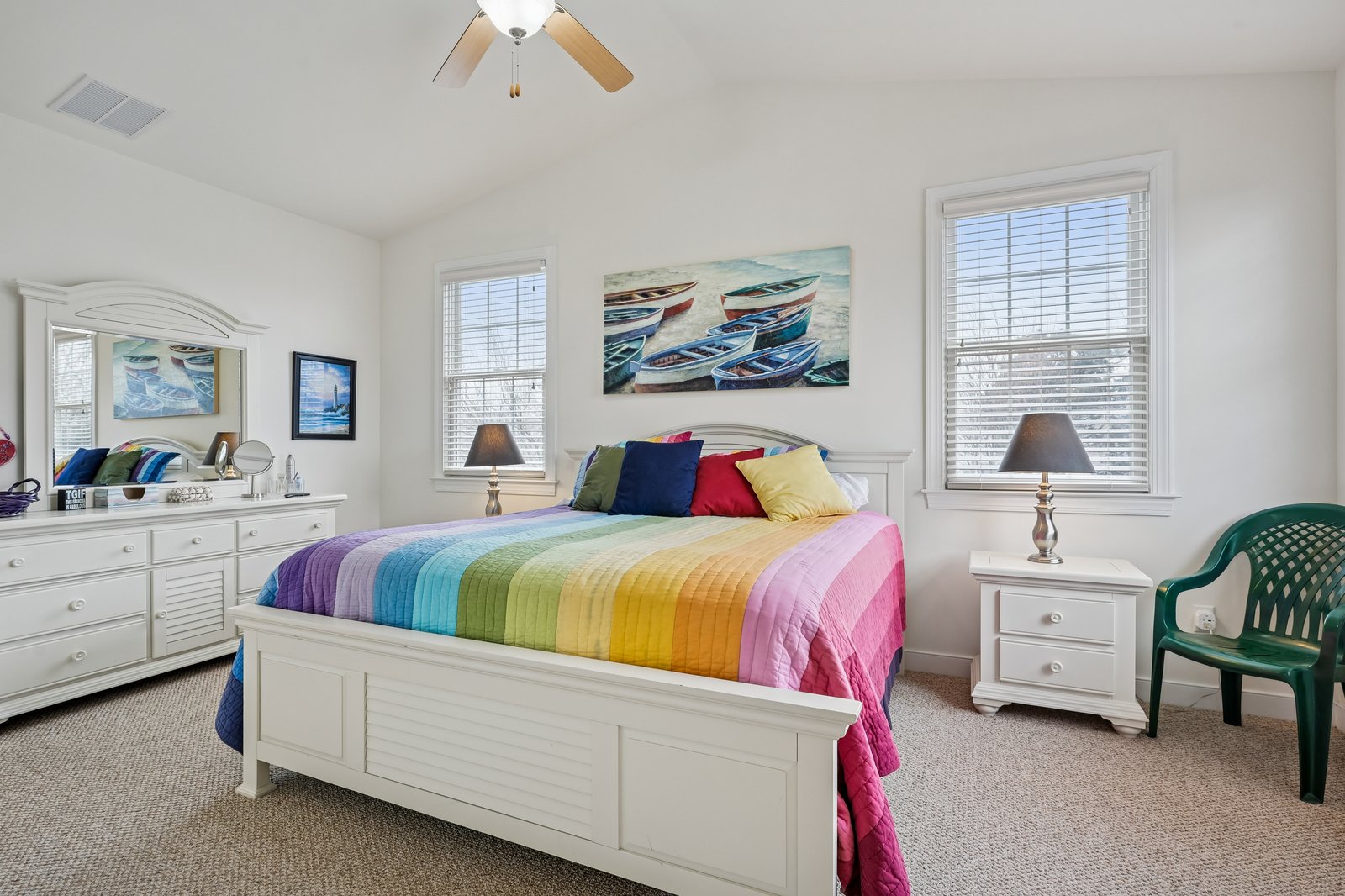 Wake up in your bright, cheerful bedroom featuring a rainbow-striped comforter and coastal artwork that brings beachside vibes indoors.