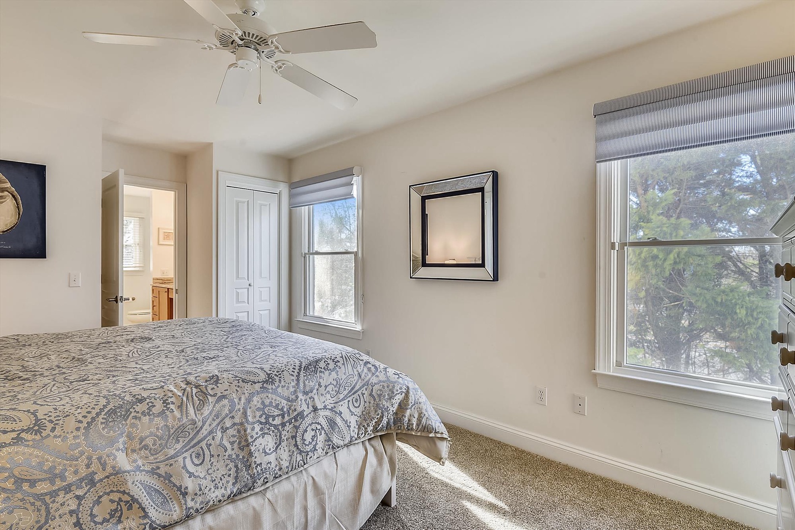 Wake up to peaceful tree views streaming through your bedroom windows, with soft carpeting underfoot and a gentle ceiling fan overhead.