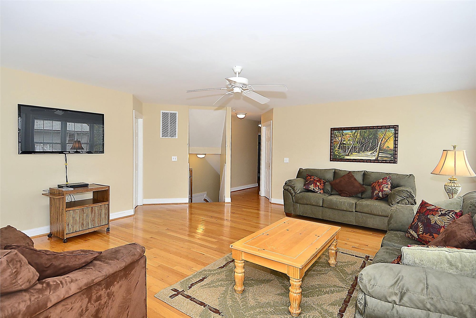 Unwind in your spacious living room with gleaming hardwood floors, comfortable seating, and a ceiling fan to keep you cool and relaxed throughout your stay.