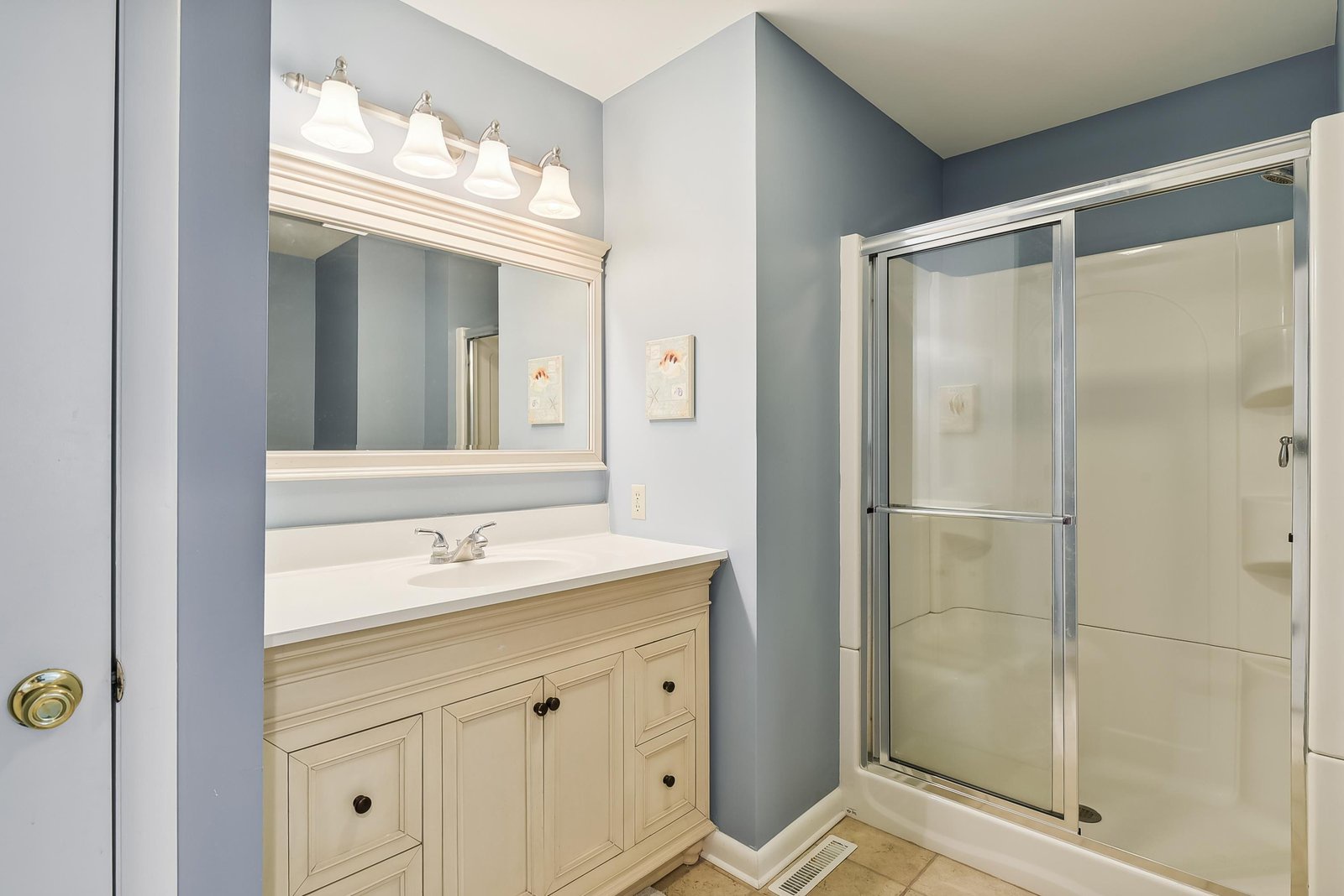 Step into your freshly updated bathroom, where soft blue-gray tones create a calm retreat. Bright vanity lighting and a spacious shower promise easy mornings and relaxing evenings.