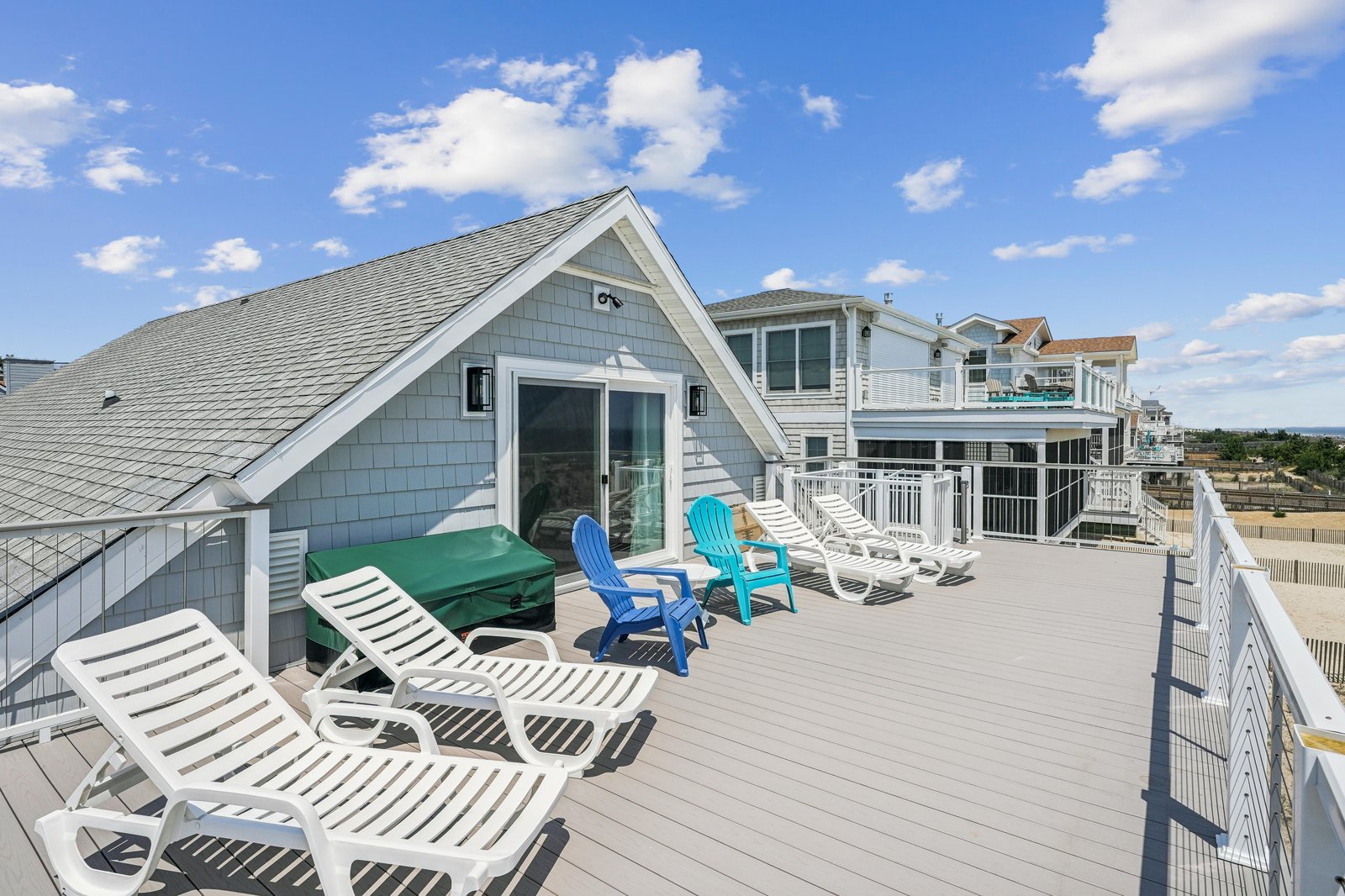 Spacious rooftop deck with lounge chairs and colorful seating where you can soak up coastal sunshine and enjoy ocean breezes.