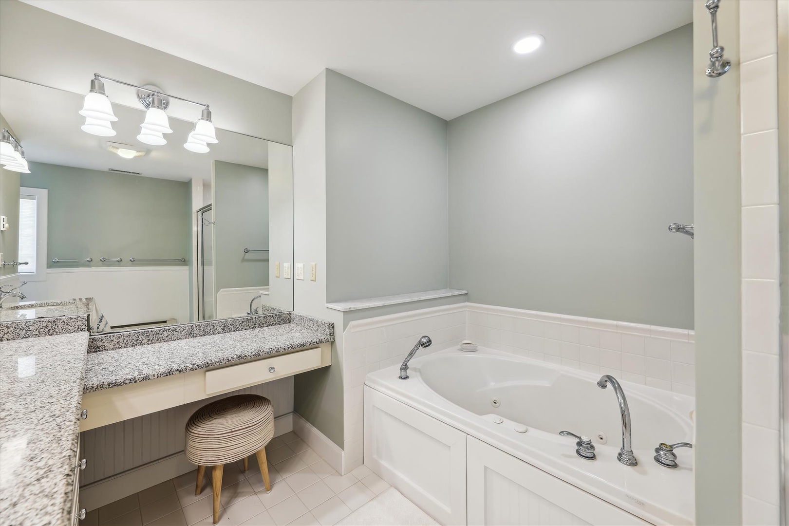 Unwind in your modern spa-like bathroom featuring a deep soaking jetted tub, sleek granite vanity, and bright lighting—your private retreat after a day exploring.