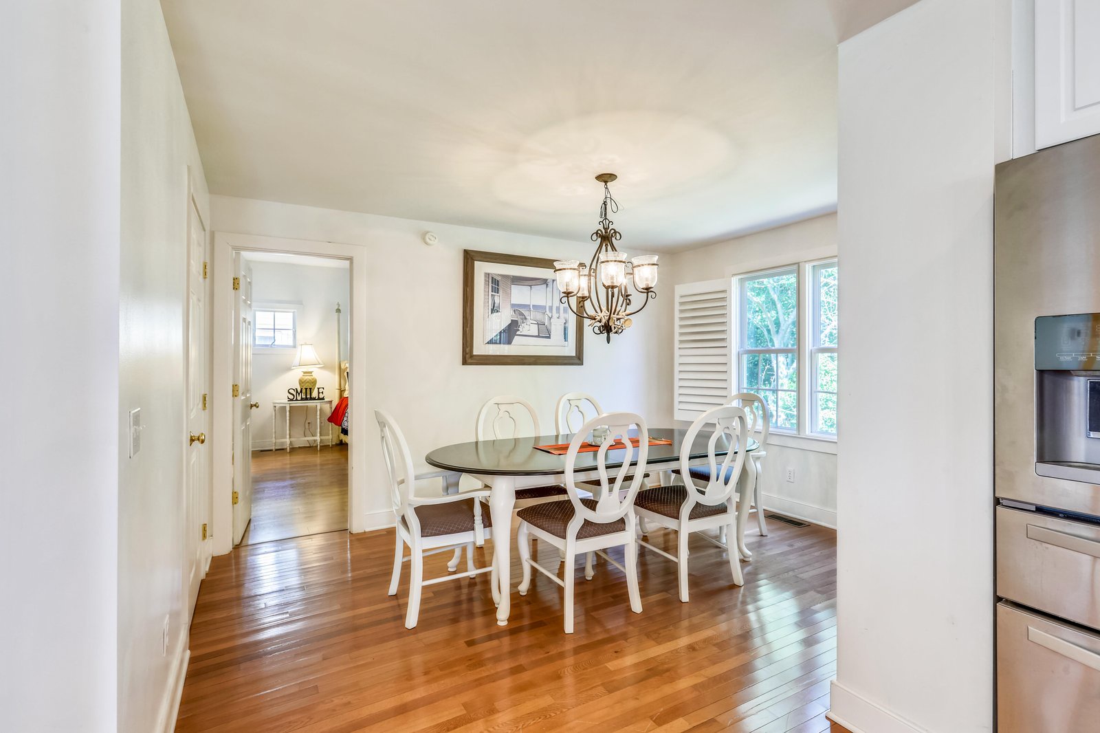 Gather around this inviting dining table under an elegant chandelier and share memorable meals with loved ones in this bright, welcoming space.