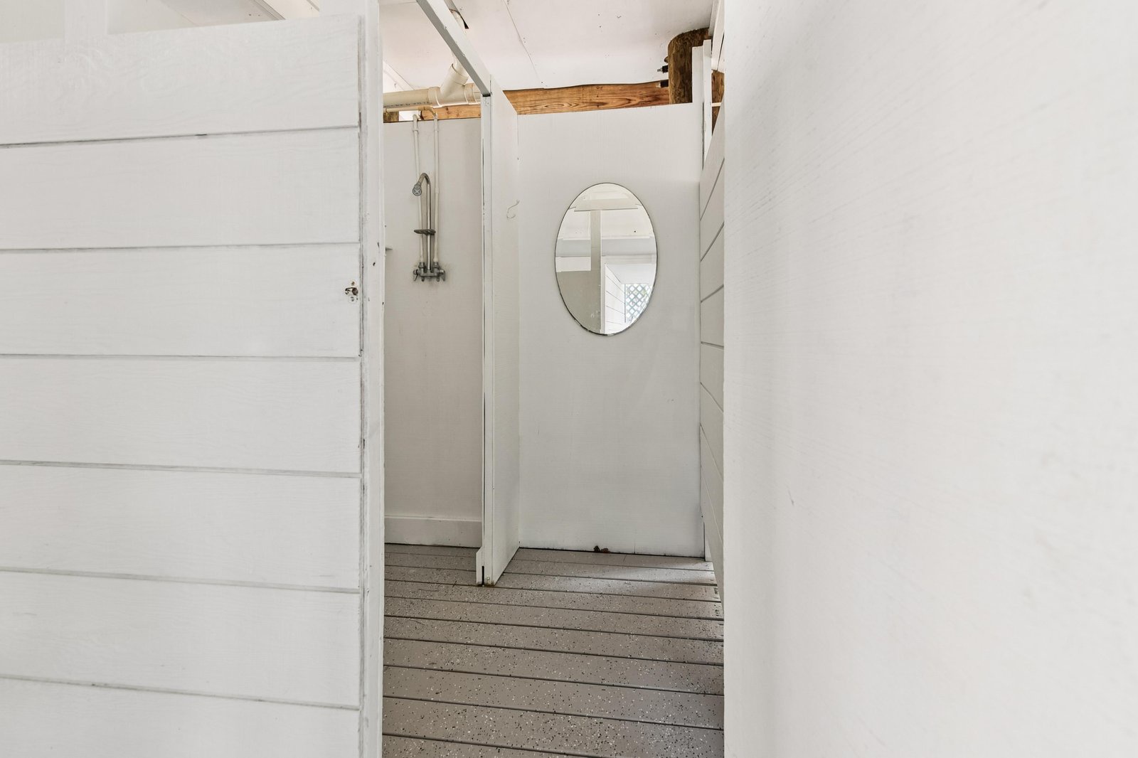 A clean, bright outdoor shower awaits after your beach days or morning swims. The simple white shiplap design and oval mirror create a fresh, coastal vibe for rinsing off.