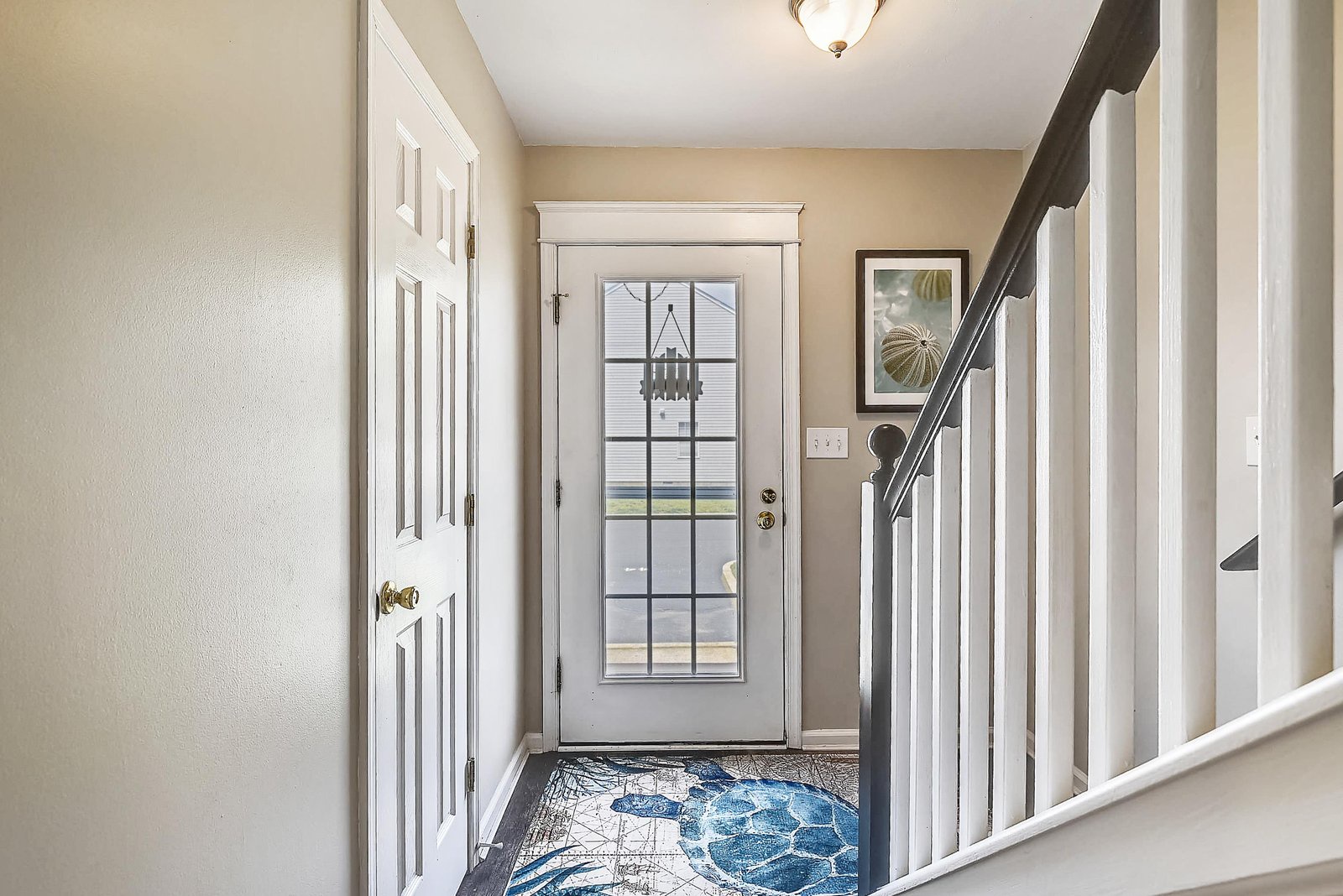 This bright entryway welcomes you with warm neutral tones, a decorative floor mat, and coastal wall art that sets a relaxed tone from the moment you arrive.