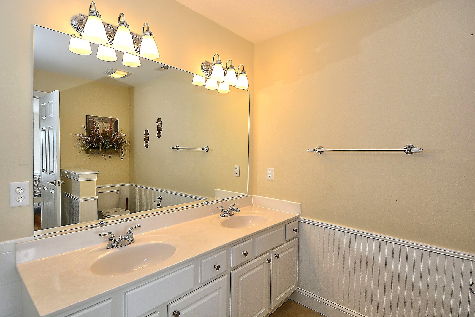 Double vanities provide plenty of space for your morning routine in this well-lit bathroom with elegant lighting and ample storage.