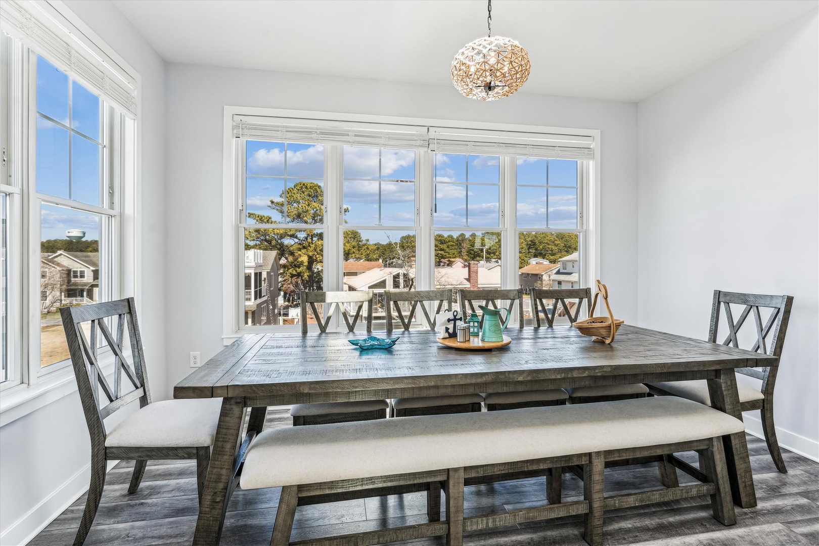 Gather around this rustic dining table as natural light floods through expansive windows. Your group can enjoy meals together while gazing at the neighborhood views beyond.