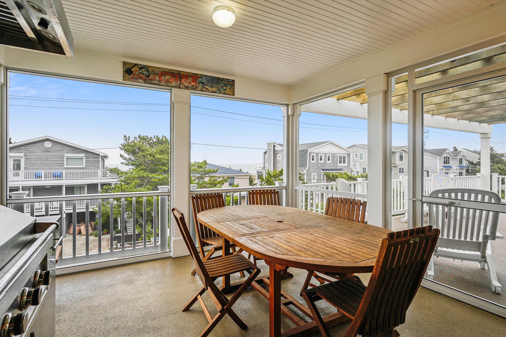 A covered screened porch offering peaceful coastal views and a welcoming dining setup—ideal for your morning coffee or alfresco meals while soaking in the neighborhood charm.