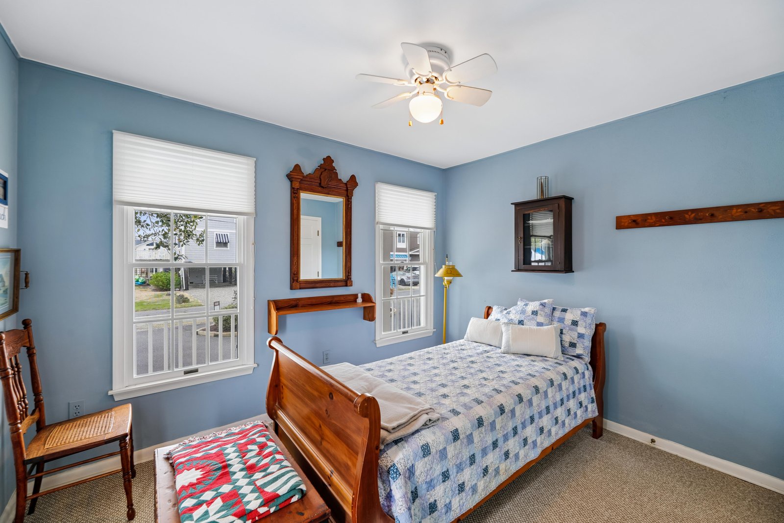 Settle into your cozy coastal bedroom with charming blue walls and natural light from two windows. The classic wooden bed and vintage touches invite restful nights.