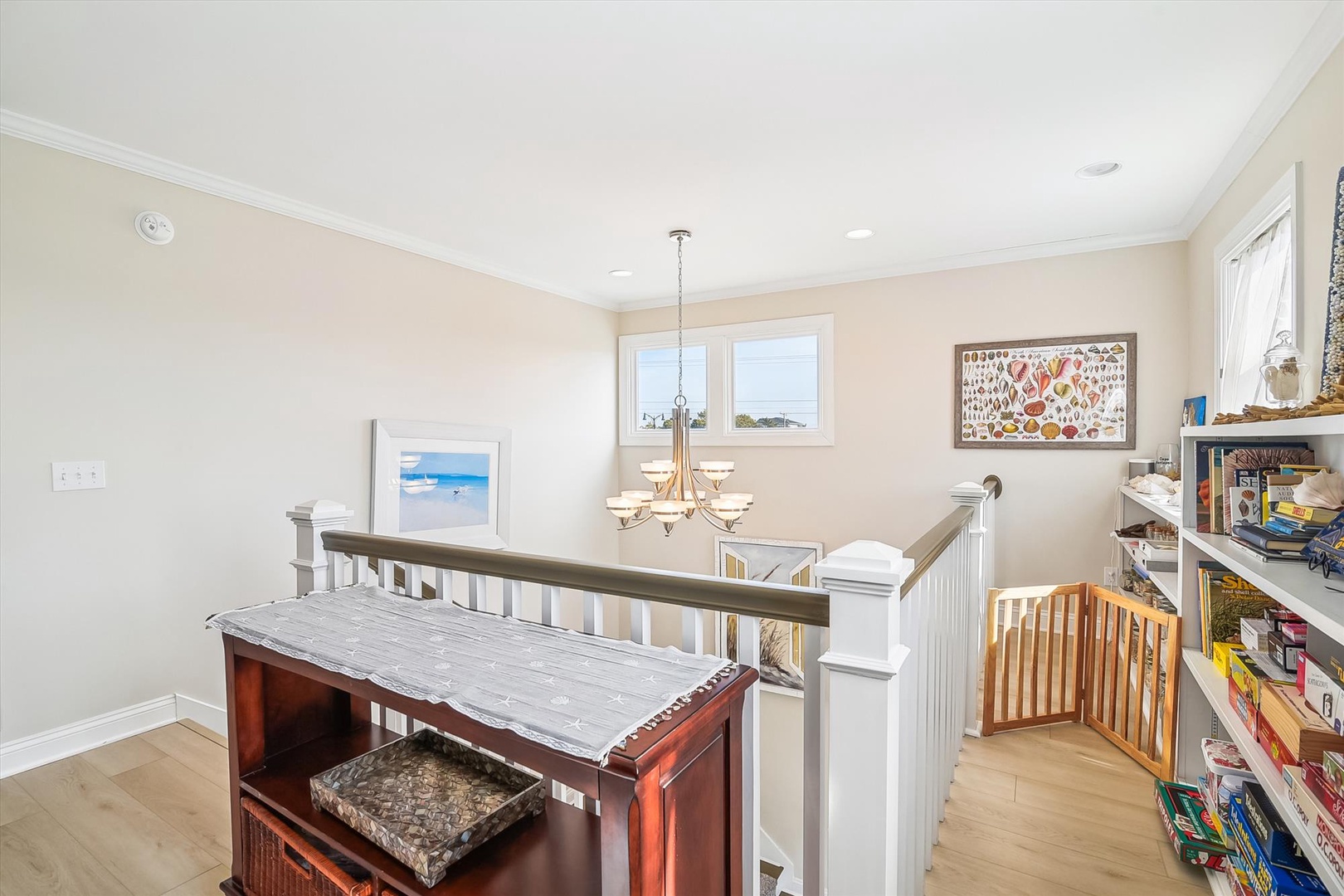 This upper-level landing offers coastal charm with ocean views through bright windows, elegant lighting, and beach-inspired art creating a warm welcome.