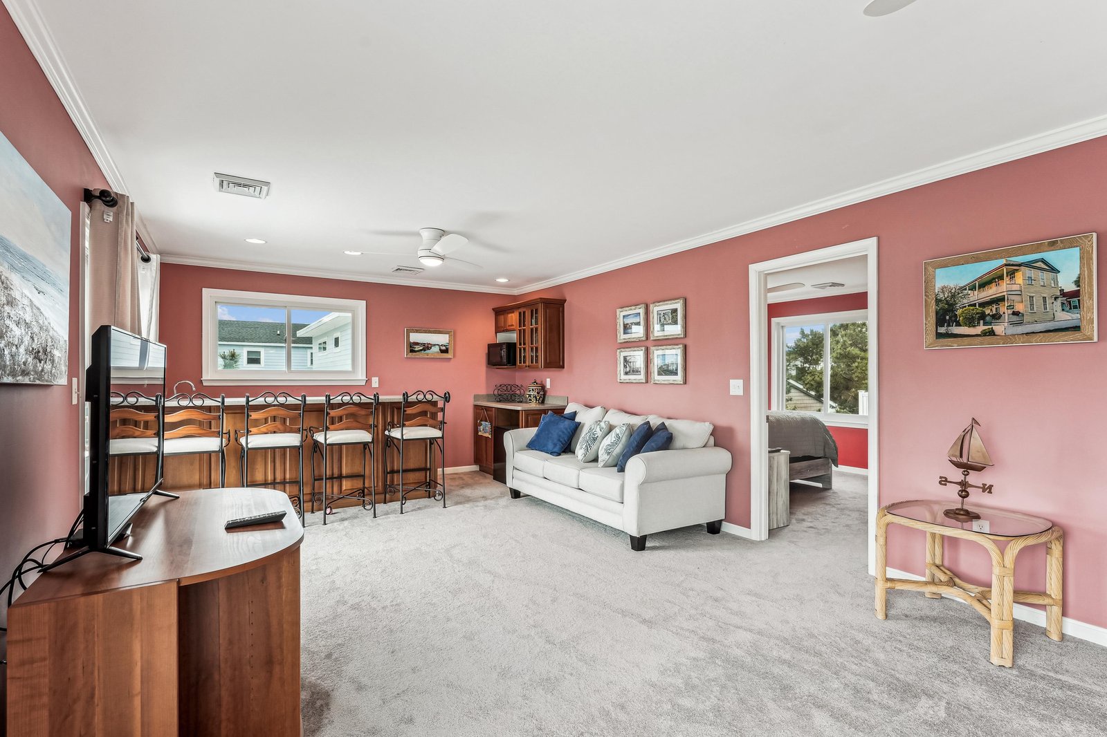 Settle into your cozy living space with warm coral walls and plenty of room to unwind. A soft sofa invites you to relax, while the bar seating offers a perfect spot for casual meals or morning coffee.